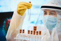 Wissenschaftlerin im sauberen Anzug mit Reagenzgläsern untersucht Coronavirus — Stockfoto