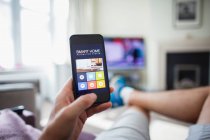 POV-Mann checkt Hausautomation auf Smartphone im Wohnzimmer — Stockfoto