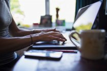 Крупним планом жінка друкує на ноутбуці, що працює з дому — стокове фото
