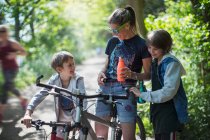 Мать и сыновья пьют воду на велосипеде в солнечном парке — стоковое фото
