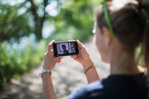 Woman video chatting with friends on smart phone screen in sunny park — Stock Photo
