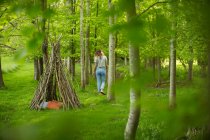 Woman near branch teepee in woodland — Stock Photo