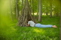 Woman laying at branch teepee in woodland — Stock Photo
