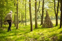 Старша жінка з гілками, що роблять прочуханку в сонячному лісі — стокове фото