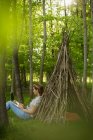 Mujer usando portátil en la rama tipi en el bosque - foto de stock