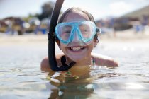 Happy girl wearing snorkel and goggles in ocean — Stock Photo