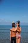 Irmão e irmã vestindo snorkels e abraços na praia — Fotografia de Stock