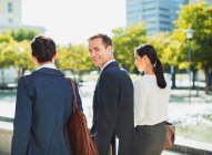 Smiling businessman walking with colleagues outdoors — Stock Photo