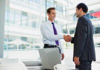 Businessmen shaking hands in office — Stock Photo
