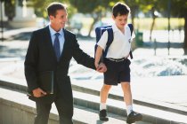Businessman and son holding hands in urban park — Stock Photo