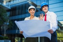 Architects reviewing blueprints outside urban building — Stock Photo