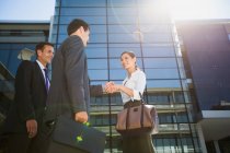 Business people shaking hands under highrise — Stock Photo