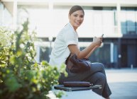 Smiling businesswoman text messaging outdoors — Stock Photo