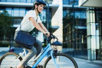Businesswoman bike riding outside urban building — Stock Photo