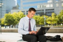 Businessman using laptop outdoors — Stock Photo