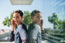 Mujer de negocios sonriente hablando en el teléfono celular al aire libre - foto de stock