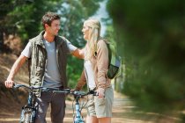 Smiling couple with mountain bikes in woods — Stock Photo