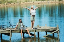 Donna esuberante con le braccia distese sul molo sul lago — Foto stock