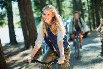 Smiling woman bike riding in woods — Stock Photo