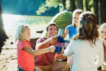 Lächelnde Familie prostet Tassen auf dem Campingplatz zu — Stockfoto