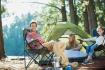 Famiglia sorridente che si rilassa al campeggio nel bosco — Foto stock