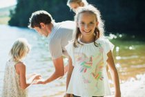 Menina sorridente com a família à beira do lago — Fotografia de Stock