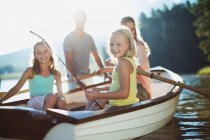 Família sorridente em barco a remos no lago — Fotografia de Stock
