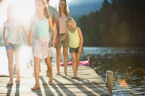 Family holding hands and walking on dock over lake — Stock Photo