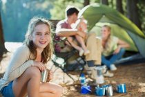 Smiling girl at campsite with family in woods — Stock Photo