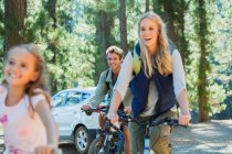 Sorridente famiglia a cavallo mountain bike nel bosco — Foto stock