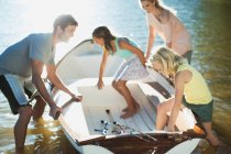 Family getting into rowboat with fishing rods on lake — Stock Photo