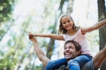 Father carrying daughter on shoulders in woods — Stock Photo