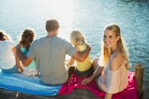 Donna sorridente con la famiglia sul molo sul lago — Foto stock