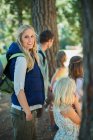 Donna sorridente escursioni con la famiglia nel bosco — Foto stock