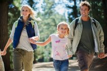 Sonriente familia cogida de la mano y corriendo en el bosque - foto de stock
