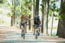 Smiling couple mountain biking in woods — Stock Photo