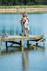 Sorrindo casal abraçando na doca sobre lago — Fotografia de Stock