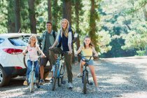 Familia sonriente con bicicletas en el bosque - foto de stock