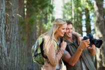 Casal olhando para a câmera digital na floresta — Fotografia de Stock
