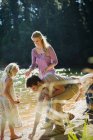 Família coletando pedras à beira do lago — Fotografia de Stock