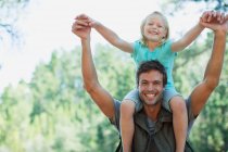 Smiling father carrying daughter on shoulders in woods — Stock Photo