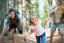 Familia cogida de la mano y corriendo en el bosque - foto de stock