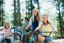 Sorrindo família andar de bicicleta na floresta — Fotografia de Stock