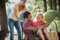 Famille souriante au camping dans les bois — Photo de stock