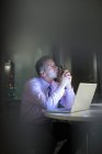 Pensive businessman working at laptop in office at night — Stock Photo