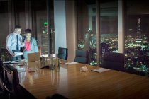Geschäftsleute sitzen nachts am Laptop im Konferenzraum — Stockfoto