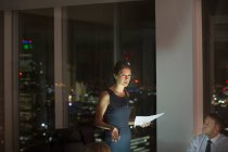 Mujer de negocios dirigiendo la reunión en la sala de conferencias por la noche - foto de stock