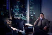 Uomo d'affari che parla al cellulare in ufficio di notte — Foto stock