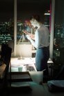 Empresária mensagens de texto com telefone celular no escritório à noite — Fotografia de Stock