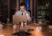 Бізнесмен працює пізно в ноутбуці в конференц-залі вночі — стокове фото